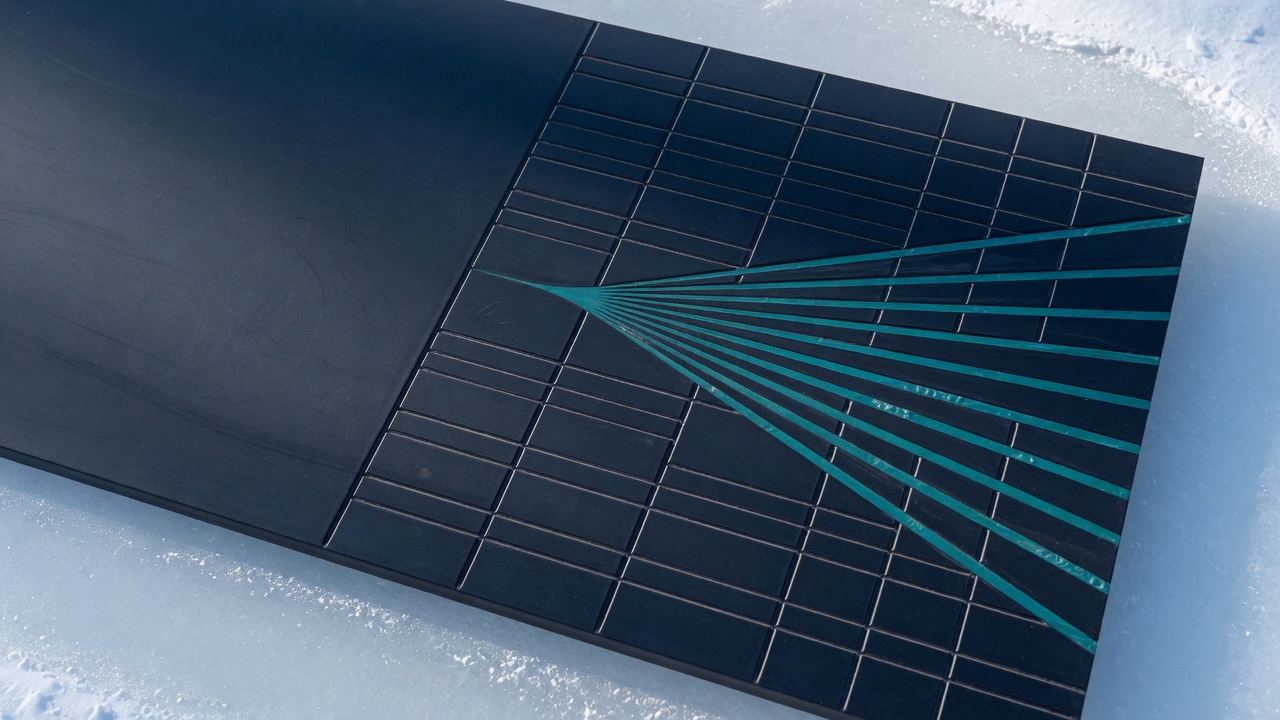 A dark ceramic slab with a carved grid and teal channels on ice-white ground. No people, no text.